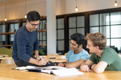 Serious teacher checking assignment of two students